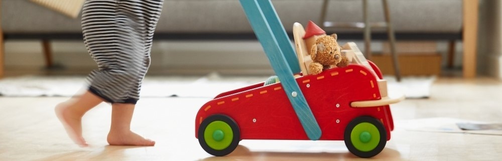 Een kind aan het spelen met duurzame, houten kinderwagen. 