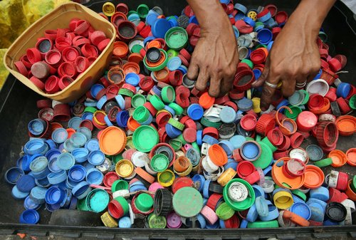 Het sorteren van plastic dopjes op kleur voor het recyclen ervan.