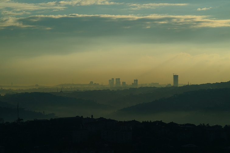 Een foto van smogvorming boven een stad, o.a. door drijfgassen afkomstig uit deo spuitbussen
