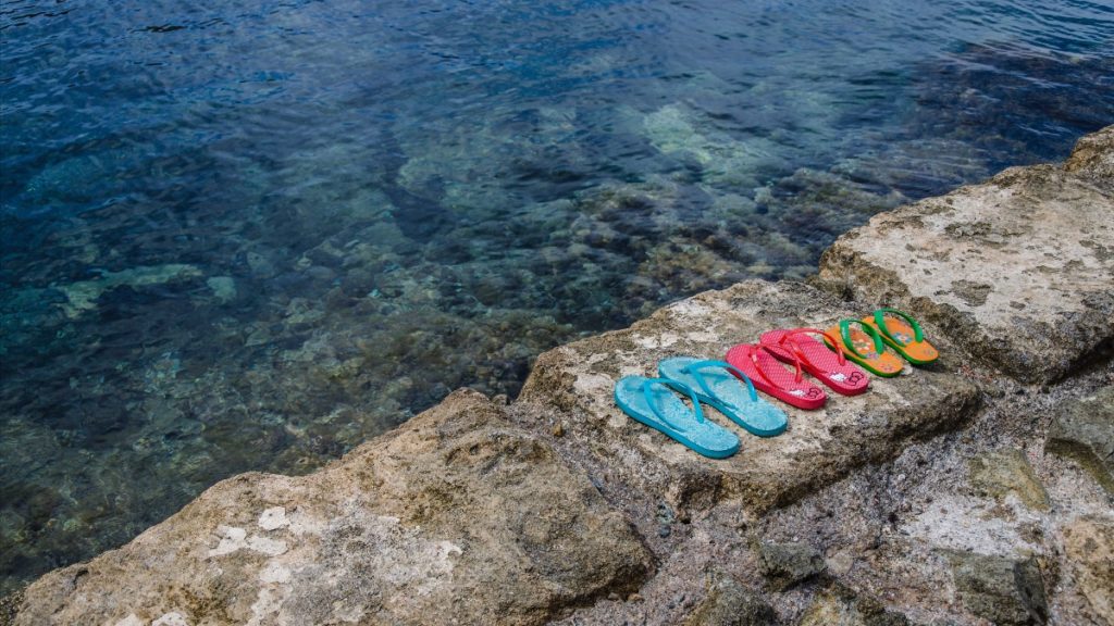 slippers op een steen naast de oceaan.jpg